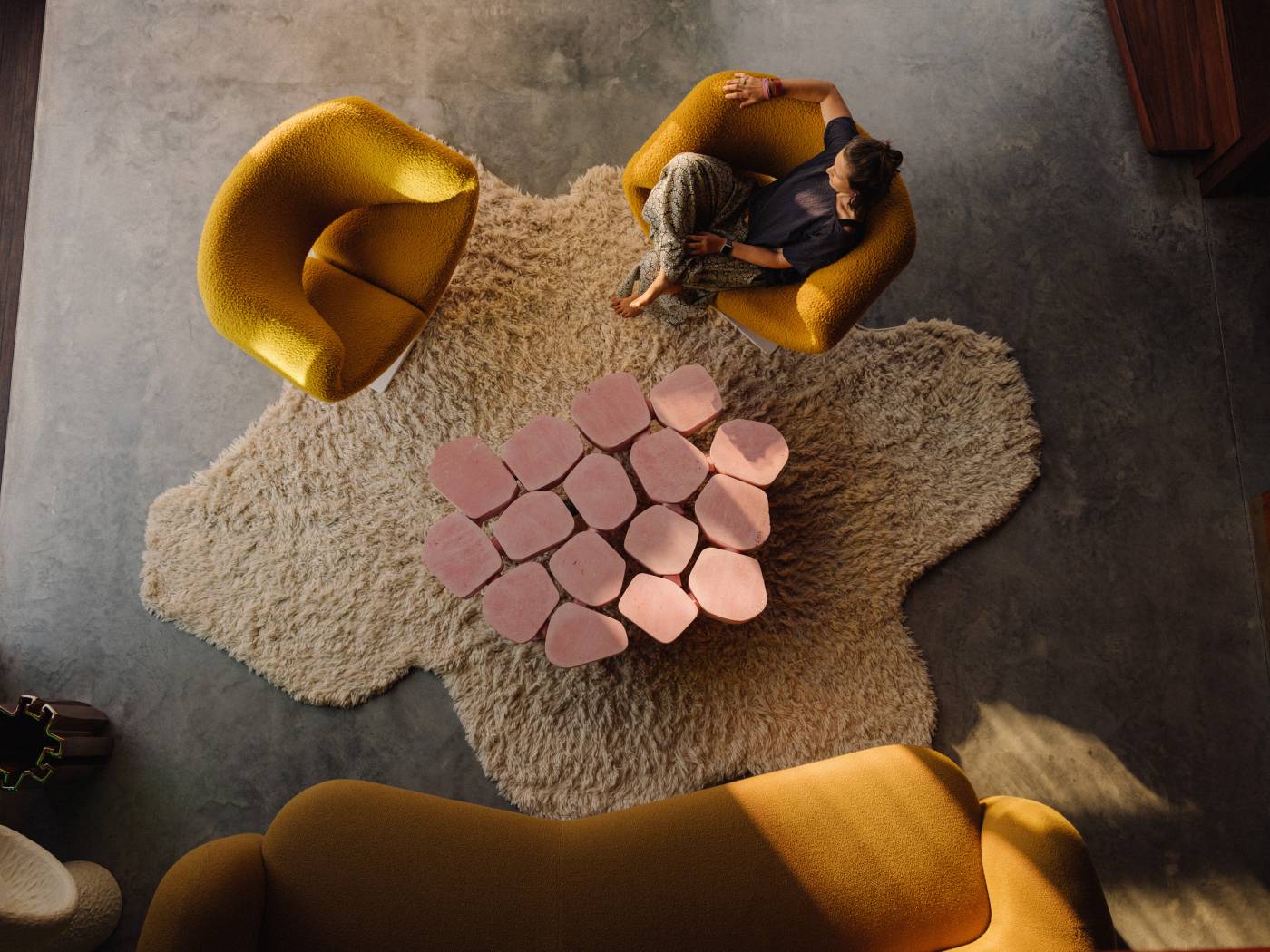 Overhead view of the ochre Gio sofa, sculptural armchairs and pink coffee table at Holocene House in Sydney.